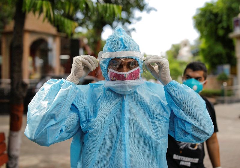 A relative wearing personal protective equipment (PPE) adjusts his protective face shield before the cremation of a man who died due to coronavirus disease (COVID-19), at a crematorium in New Delhi, India August 22, 2020. REUTERS/Adnan Abidi